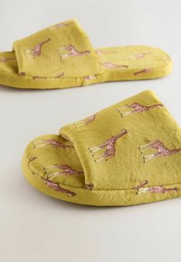 Yellow slippers with giraffe pattern, soft texture, round toe, and open back design. Suitable for indoor use.