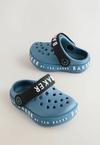 Modré gumené kroksy majú ventilačné otvory, čierny remienok s textom "BAKER" a textúrovanú podrážku s bielymi brandingovými akcentmi.