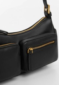 Sac en cuir noir avec deux poches zippées à l'avant et une fermeture éclair dorée. Présente une surface texturée et un design incurvé. Accents de quincaillerie métallique.