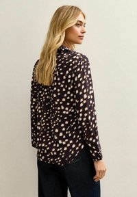Lange mouwen blouse van lichtgewicht stof, met een donker marineblauwe achtergrond en een wit en tan penseelstrekenpatroon, in een relaxte pasvorm.