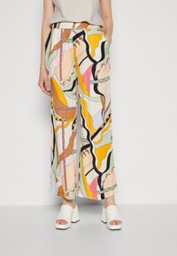 Färgglada vida byxor med ett djärvt abstrakt mönster i nyanser av gult, rosa, grönt och svart, tillverkade av lätt tyg.