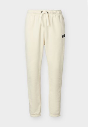 Väriltään luonnonvalkoiset, nyörillä kiristyvät collegehousut, joissa on joustava vyötärönauha ja lahkeensuut sekä pieni musta brändilogo oikeassa lonkassa.