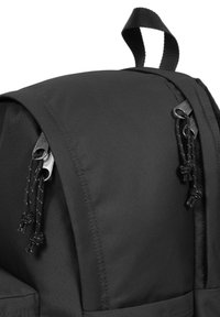 Musta nailonireppu pyöreällä ylhäällä, jossa on kaksi metallista vetoketjupullaa ja mustia naruakkentteja. Pintakuvioitu kangaspinta, kestävä yläkahva.