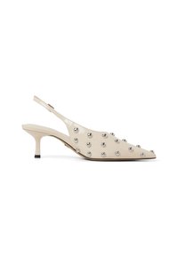 Beige patent leather slingback-korkokengät, joissa on teräväkärkinen muotoilu, hopeiset dome-nuget ja kitten-korko. Ominaisuuksiin kuuluu kapea nilkkaremmi.