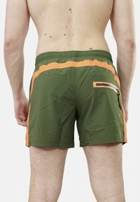 Pantaloni da bagno verdi con dettagli arancioni, dotati di tasca laterale con zip e cintura elastica. Tessuto leggero e ad asciugatura rapida.