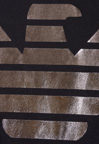 Svart tyg med metalliska silverränder och former med en texturerad yta. Designen är djärv och grafisk med släta kanter.