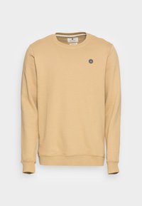 Sudadera de color beige claro hecha de tela suave, con cuello redondo y puños acanalados, y un pequeño logo gráfico redondo en el pecho.
