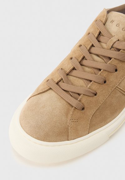 Καμήλα σουέντ αθλητικό παπούτσι με στρογγυλή μύτη, υφή και κορδόνια στο ν ίδιο τόνο. Διαθέτει λευκή λαστιχένια σόλα και διακριτική σήμανση στη γλώσσα.