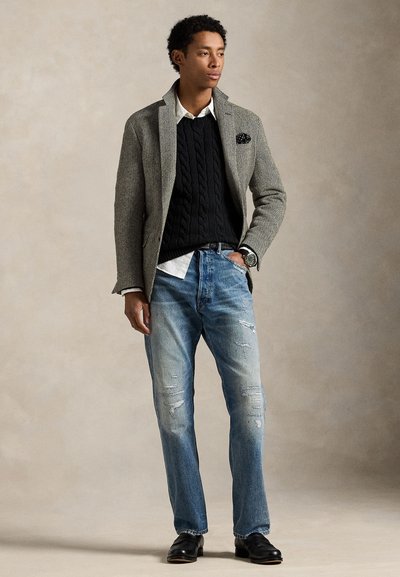 Pilkas žuvies kaulo rašto švarkas, juodas pintas megztinis, baltas marškinis, dryžuotos šviesiai mėlynos spalvos džinsai su dėvėjimo ženklais, odiniai batai, riešo laikrodis ir kišenėlės skarelė.