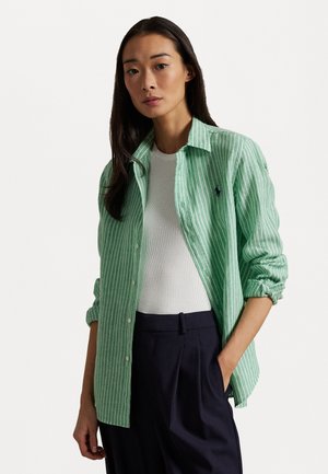 Groen en wit gestreepte button-up shirt, lichtgewicht stof, ontspannen pasvorm, opgerolde mouwen. Gecombineerd met een wit topje en donkere broek.