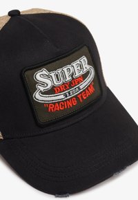Sort baseball cap med en struktureret khaki mesh ryg. Frontpatchen viser "SUPER DRY JPN" med "RACING TEAM" i rød broderi.
