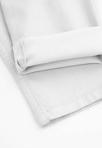 Szary bawełniany materiał o gładkiej fakturze, z podwiniętymi mankietami i widocznymi szwami, leżący płasko na białym tle.