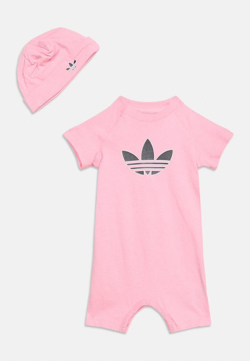 Tutina rosa per neonati con logo Adidas trifoglio nero al centro, abbinata a cappellino rosa coordinato con logo più piccolo sul lato.