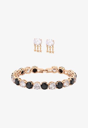 Bransoletka w kolorze złotym z naprzemiennie ułożonymi czarnymi i przezroczystymi okrągłymi kamieniami, zestawiona ze złotymi kolczykami z przezroczystymi kamieniami i wiszącymi zawieszkami w kształcie gwiazdek.