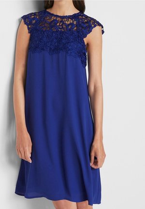 Sukienka bez rękawów w królewskim niebieskim kolorze z misternymi koronkowymi zdobieniami na górnej części klatki piersiowej i ramionach, delikatnie opadająca tuż ponad kolano.
