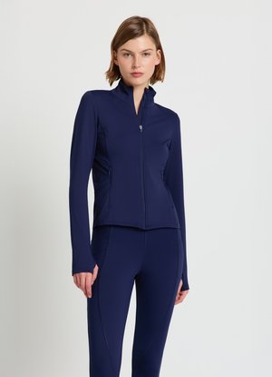 Veste de sport zippée bleu marine à manches longues, dotée d'un col montant et d'un tissu texturé. Des poches sont situées sur les côtés.