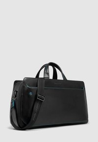 Borsa in pelle nera con accenti blu, forma rettangolare, doppi manici e tracolla rimovibile. Presenta un design elegante e un dettaglio con logo.