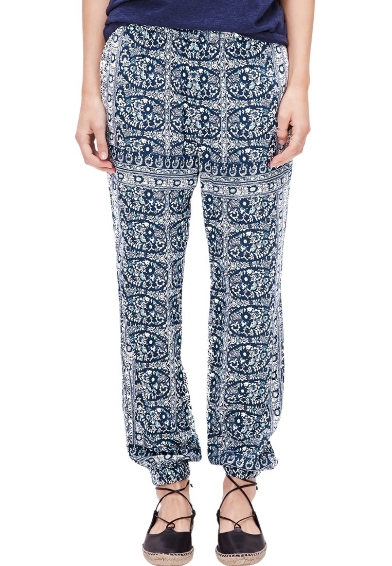 Pantalons à motifs bleu et blanc avec une coupe ample, une taille élastique et des poignets froncés, présentant des designs floraux et des motifs de carreaux ornés.