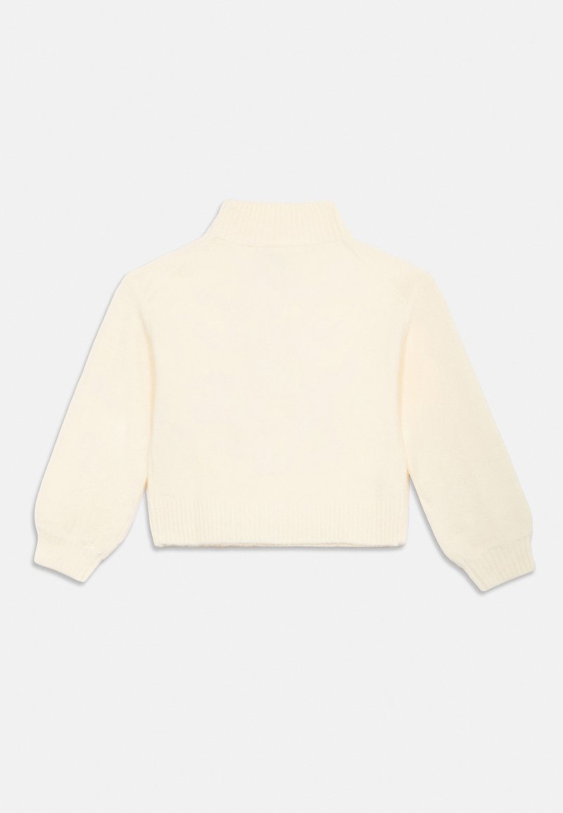 Suéter corto color crema con cuello alto, puños y dobladillo acanalados, hecho de un suave material de punto. La parte trasera es lisa y sin adornos.