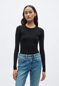 Zwart bodysuit met lange mouwen, een gladde textuur en een ronde hals, gecombineerd met lichtblauwe denim jeans met een losse pasvorm en voorzakken.
