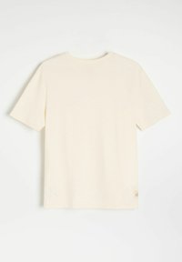 Kremowa koszulka z krótkim rękawem, okrągłym dekoltem i fakturowanym materiałem. Posiada małą metkę z logo na dolnym końcu.