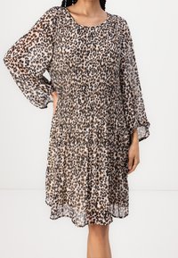 Leopard print dress with long, puffed sleeves. Made from lightweight, sheer fabric, featuring a smocked waist and tiered design.