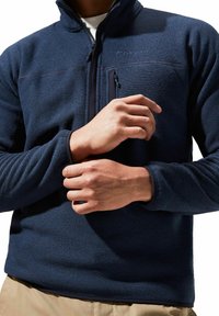 Marineblauer Fleece-Pullover mit halbem Reißverschluss-Kragen, strukturiertem Stoff und einer Brusttasche. Verfügt über elastische Bündchen und eine figurbetonte Silhouette.