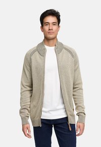 Lichtbeige gebreide cardigan met een rits aan de voorkant, geribbelde manchetten en kraag. Heeft een gladde textuur en contrasterende stiksels.