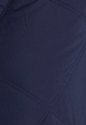 Tessuto trapuntato di colore blu navy con un motivo a diamante e cuciture visibili. La texture appare liscia con una leggera lucentezza.