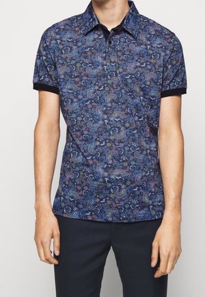 Herren-Polohemd mit kurzen Ärmeln, dunkelblauem Paisley-Muster, schwarzem Kragen und Ärmelbündchen, kombiniert mit dunkler Hose.