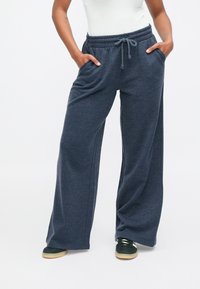 Dark gray, wide-leg sweatpants with an elastic waistband and drawstring. Features two side pockets and a soft texture.