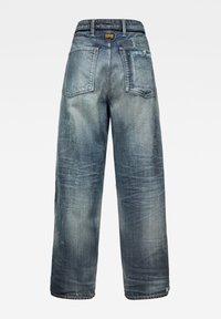 Bakvy av löst sittande, blekta blå denimjeans med två bakfickor och en svart etikett på midjebandet.