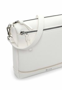 Hvid læderhåndtaske med tekstureret finish, der har en øverste lynlås, justerbar rem og hardware i sølvfarve.