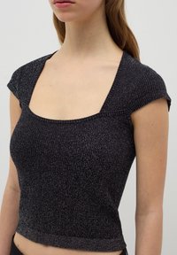 Top corto negro ajustado con escote cuadrado y mangas corta, hecho de una tela texturizada con un brillo sutil.