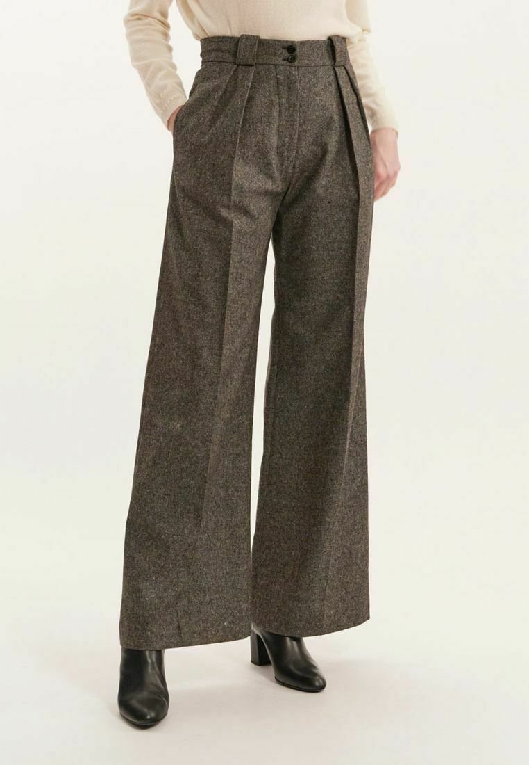 Un pantalon large texturé gris avec une taille haute, présentant des plis avant doubles et deux boutons, associé à des bottes noires à talons.