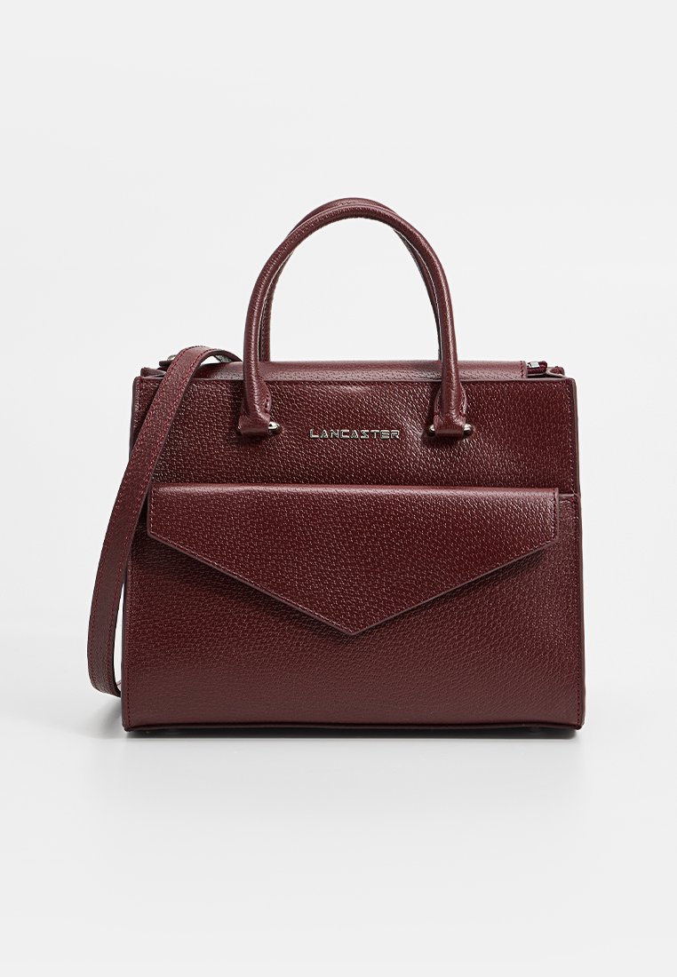 Sac à main en cuir texturé bordeaux avec poignées supérieures, une bandoulière amovible et une poche frontale angulaire. Accents en métal argenté visibles.