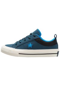 Modrá teniska s texturovaným svrškem, černými síťovanými doplňky, bílou gumovou podrážkou a modrým logem hvězdy. Má kulaté tkaničky a poutko na zatahování.