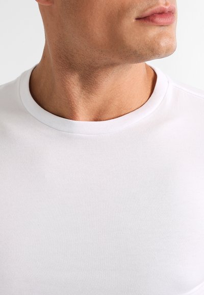 T-shirt en coton blanc avec un col rond et une texture lisse, ajusté au niveau du col avec des coutures subtiles.