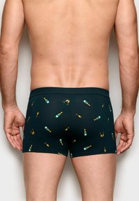 Schwarze Boxershorts mit einem Muster aus gelben Champagnerflaschen und Gläsern, aus weichem, dehnbarem Stoff gefertigt. Mittelhoher Schnitt mit einem bequemen Bund.