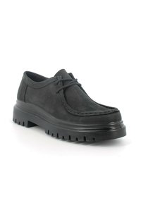 Scarpe in pelle nera con forma arrotondata, superficie testurizzata e suola in gomma spessa con scanalature orizzontali e dettagli cuciti.