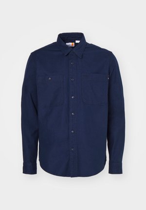 Camisa de botones azul marino de algodón, con cuello puntiagudo, mangas largas, dos bolsillos en el pecho y dobladillo recto.