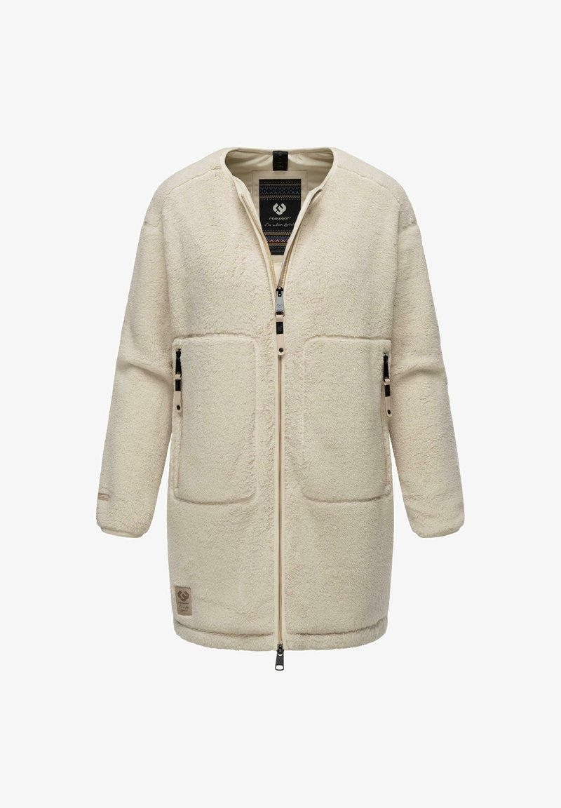 Krēmpā krāsā fliša jaka ar priekšējo rāvējslēdzēju, divām lielām ieliktņu kabatām un teksturētu virsmu. Iezīme ir ar zīmola etiķeti netālu no apakšmalas.