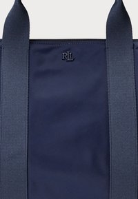 Laivastonsininen kangaskassi vetoketjullisella suljinnalla, jossa on kaksi tukevat sivukahvaa ja keskellä kohopainettu "RLL"-logo. Sileä pinta.