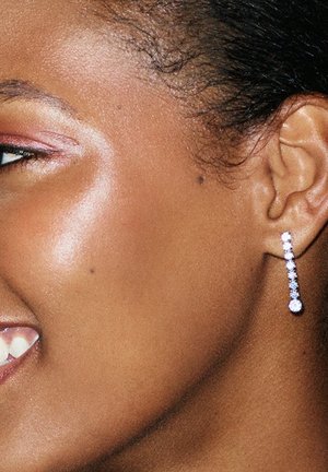 Orecchini pendenti in argento caratterizzati da una linea verticale di piccoli diamanti rotondi, che culminano in un diamante più grande nella parte inferiore.