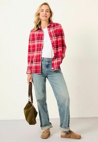 Red plaid flannel shirt, white t-shirt beneath, light wash jeans, tan clogs, and an olive green bag with a brown strap. Casual outfit.