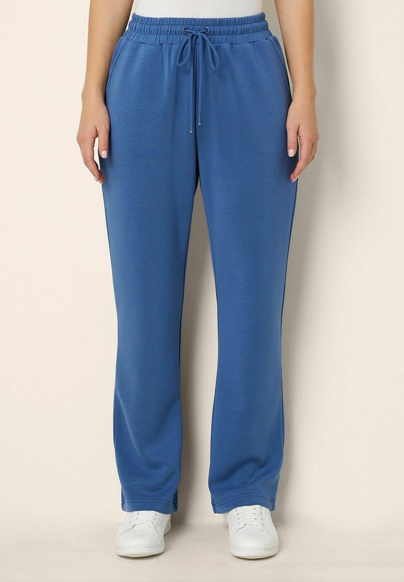 Blue sweatpants with a drawstring waist, featuring a smooth texture, relaxed fit, and paired with white sneakers.