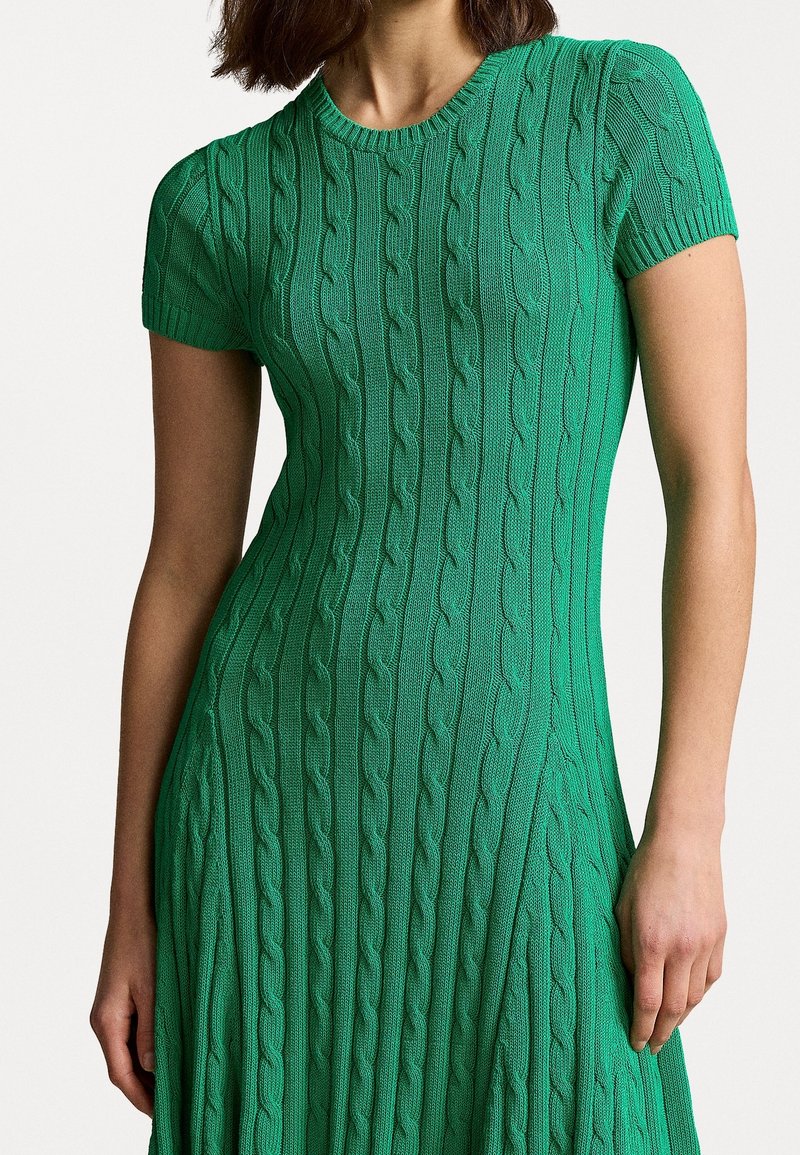 Robe verte en maille avec un motif côtelé, dotée d'un col rond et de manches courtes, un corsage ajusté menant à une jupe évasée.