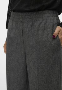 Grå, texturerade byxor med elastisk midja och sidofickor. Tyget har ett subtilt mönster och en något lös passform.