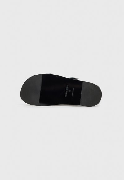 Sort lædersandal med en glat mat overflade, flad gummisål og justerbar rem med sølvfarvede hardwaredetaljer.
