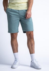 Lichtblauwe shorts van katoen met een gladde structuur, voorzien van zijzakken en een rechte snit, gecombineerd met witte sneakers en korte sokken.